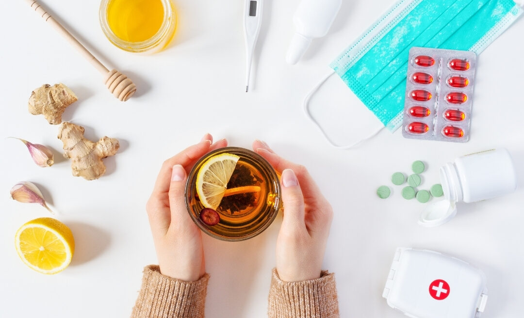 Tea with ginger, lemon, and flu prevention items like masks and pills on a table, representing flu prevention and precautions.