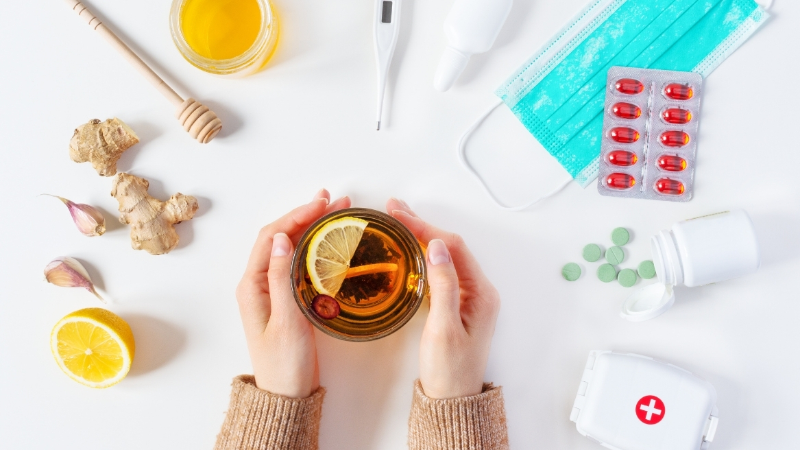 Tea with ginger, lemon, and flu prevention items like masks and pills on a table, representing flu prevention and precautions.