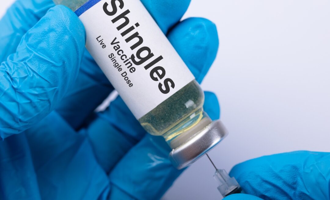 Shingles vaccine vial being held by gloved hands, highlighting essential information on shingles prevention and Shingles travel vaccines for travellers.