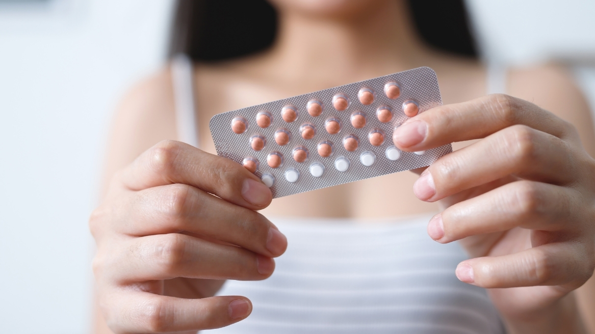 Close-up of a person holding a blister pack of contraceptive pills, part of a detailed women’s health guide at Hodgson Pharmacy.